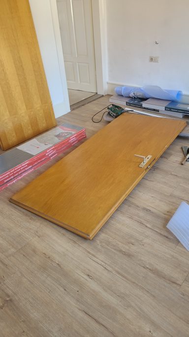 Ein offenes Zimmer mit einem Holzbrett auf dem Boden und Baustellenmaterialien.